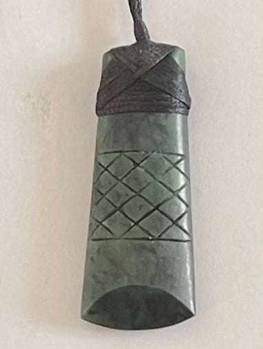 Greenstone pendant with braided design on a white background