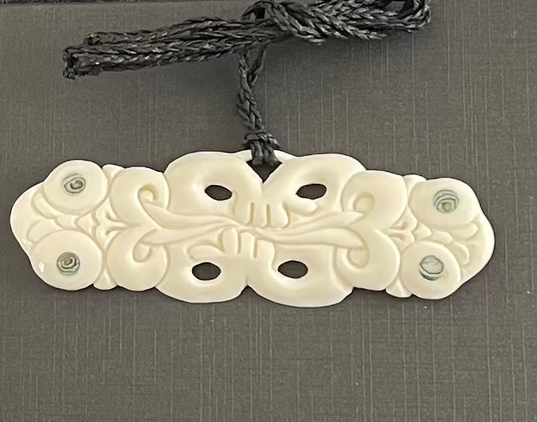 Carved bone pendant on a gray background