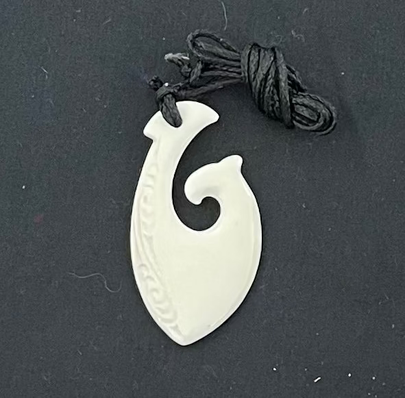 White bone pendant with spiral design on a black background