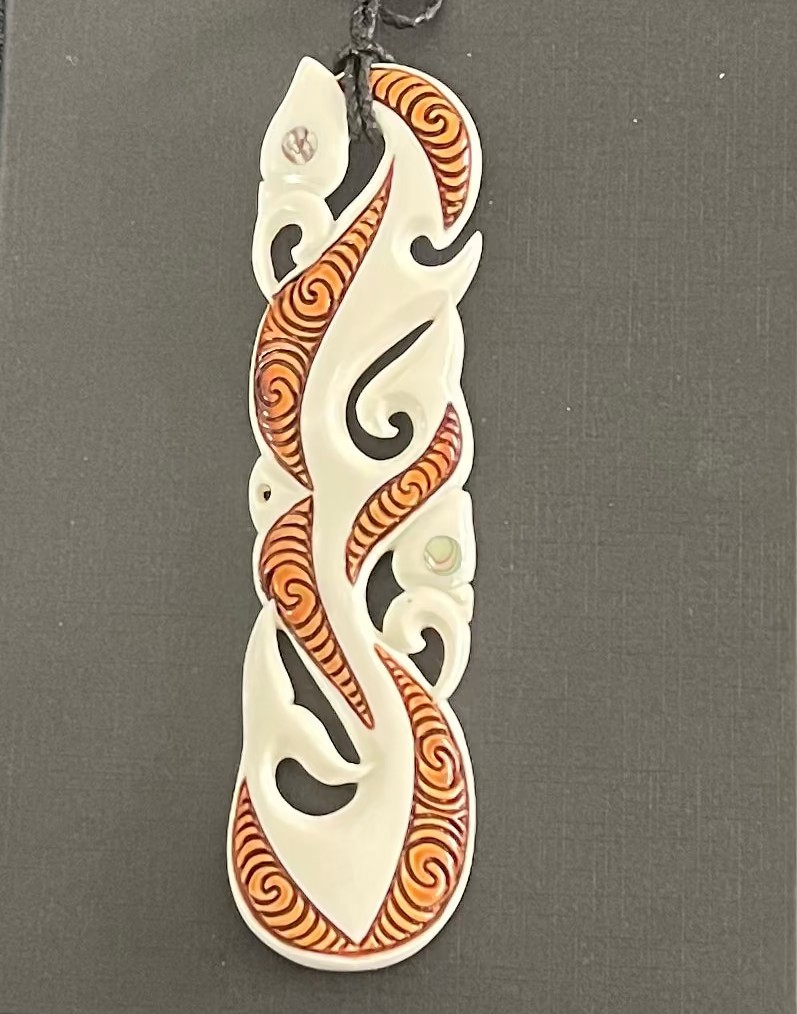 Decorative BONE pendant with intricate orange and white patterns on a gray background