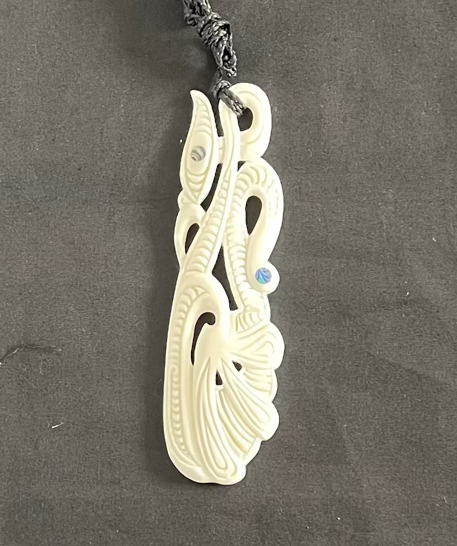 Decorative MANAIA pendant with intricate design on a dark gray background