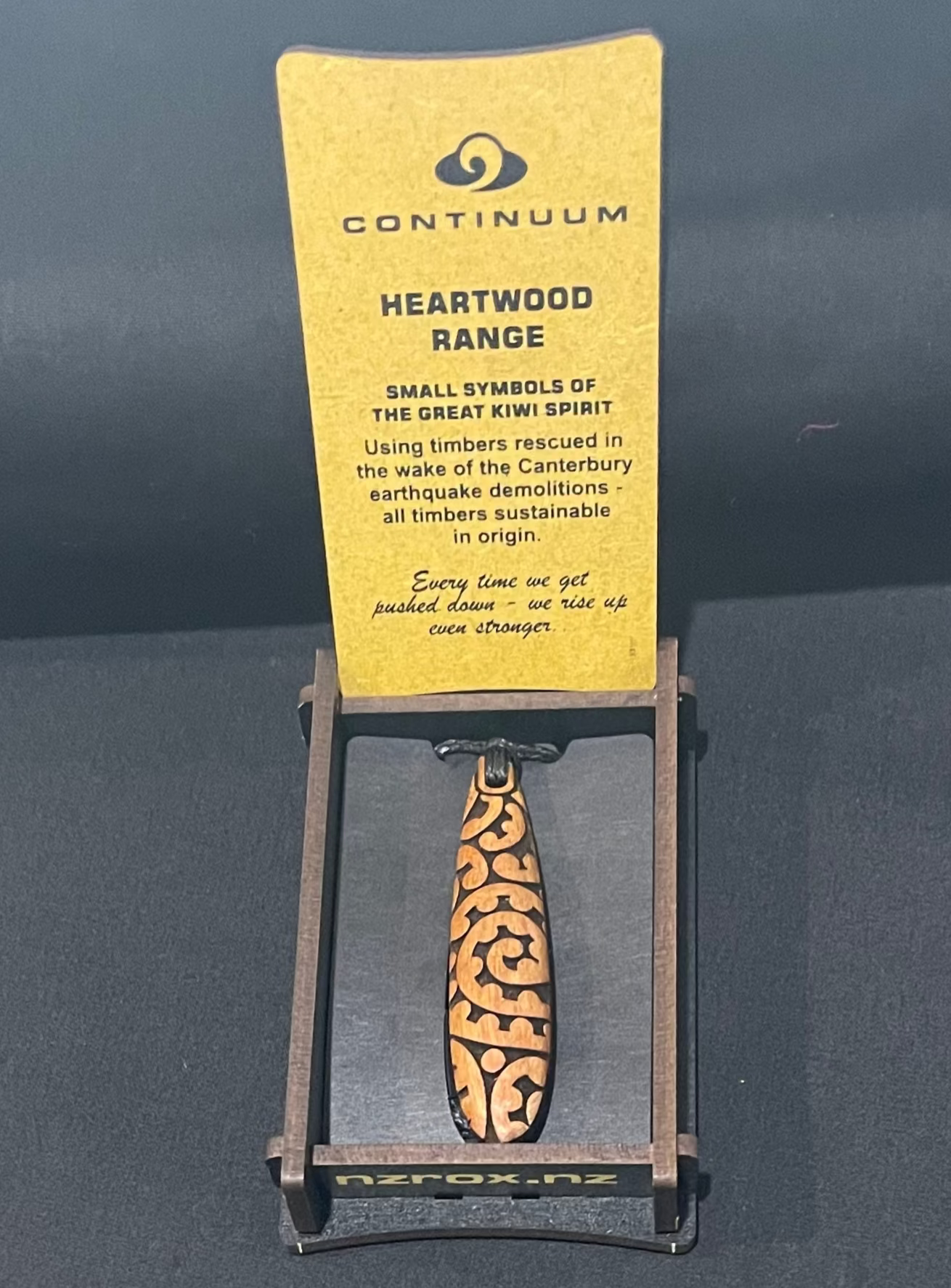 Wooden pendant on a stand with a yellow card displaying 'Continuum' branding