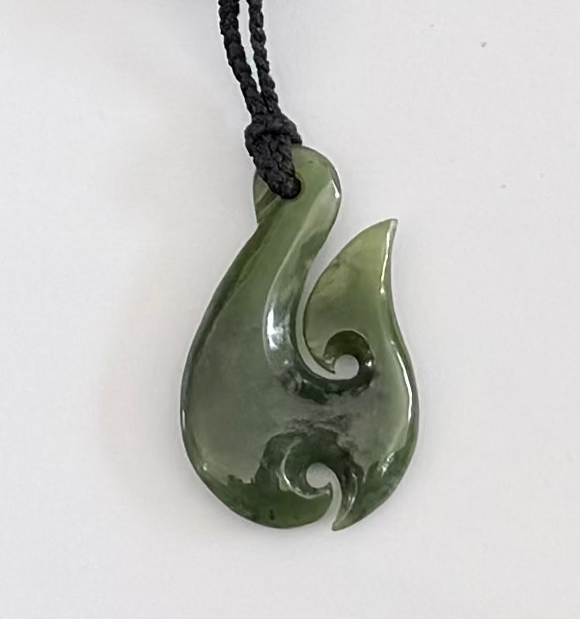 Greenstone hook jade pendant on a white background