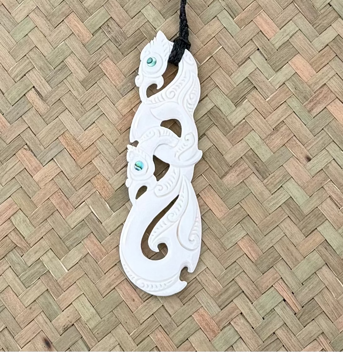 White bone carvings on a black cord against a woven mat background