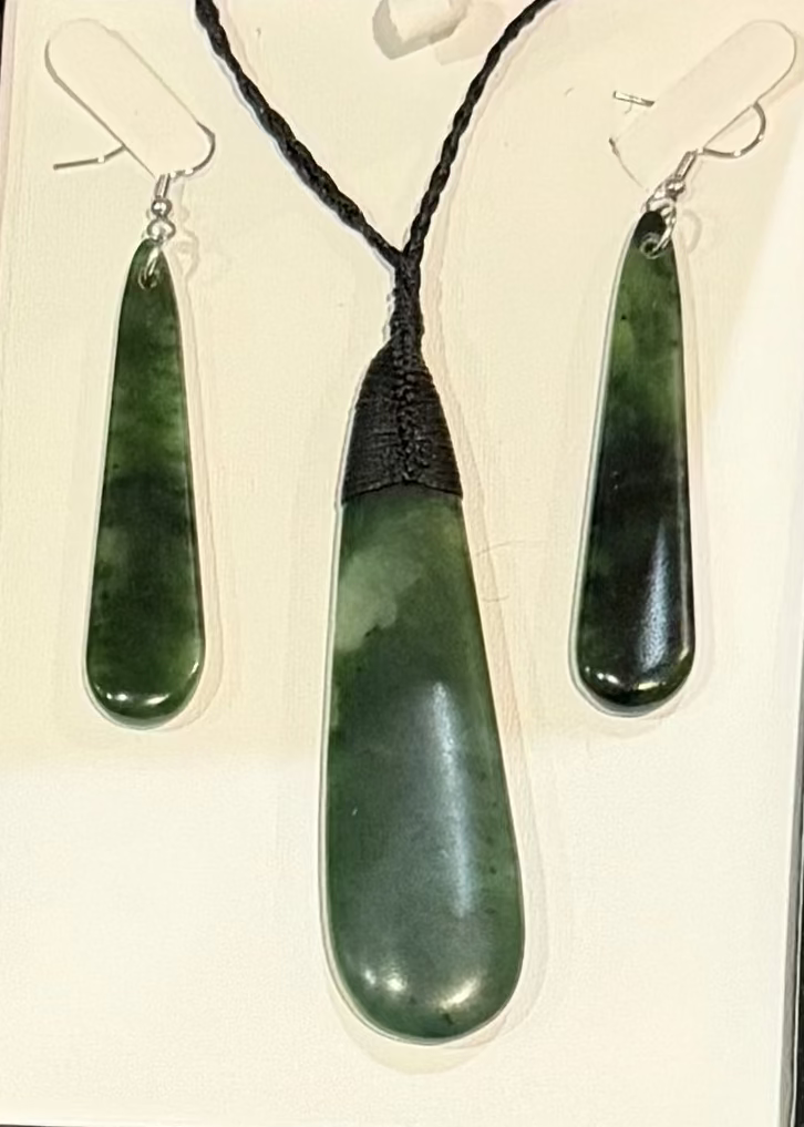 Jewelry pounamu set with pendant and earrings in a box on a textured surface