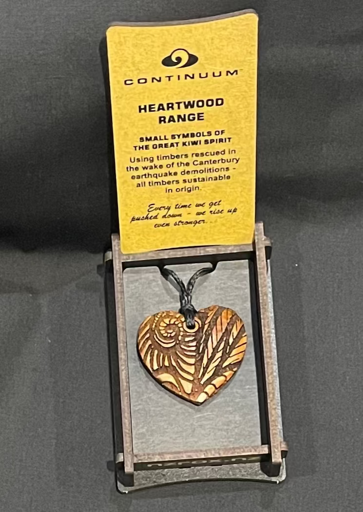 Heart-shaped pendant on a card with 'Continuum' branding on a dark background
