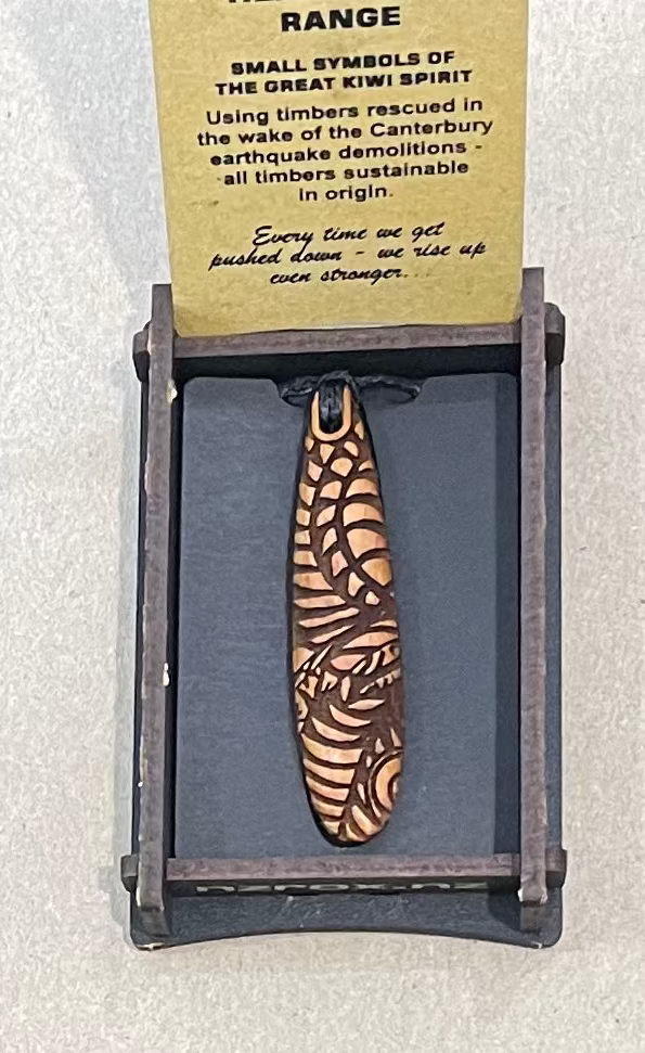 Wooden pendant with zebra pattern on a display card with text