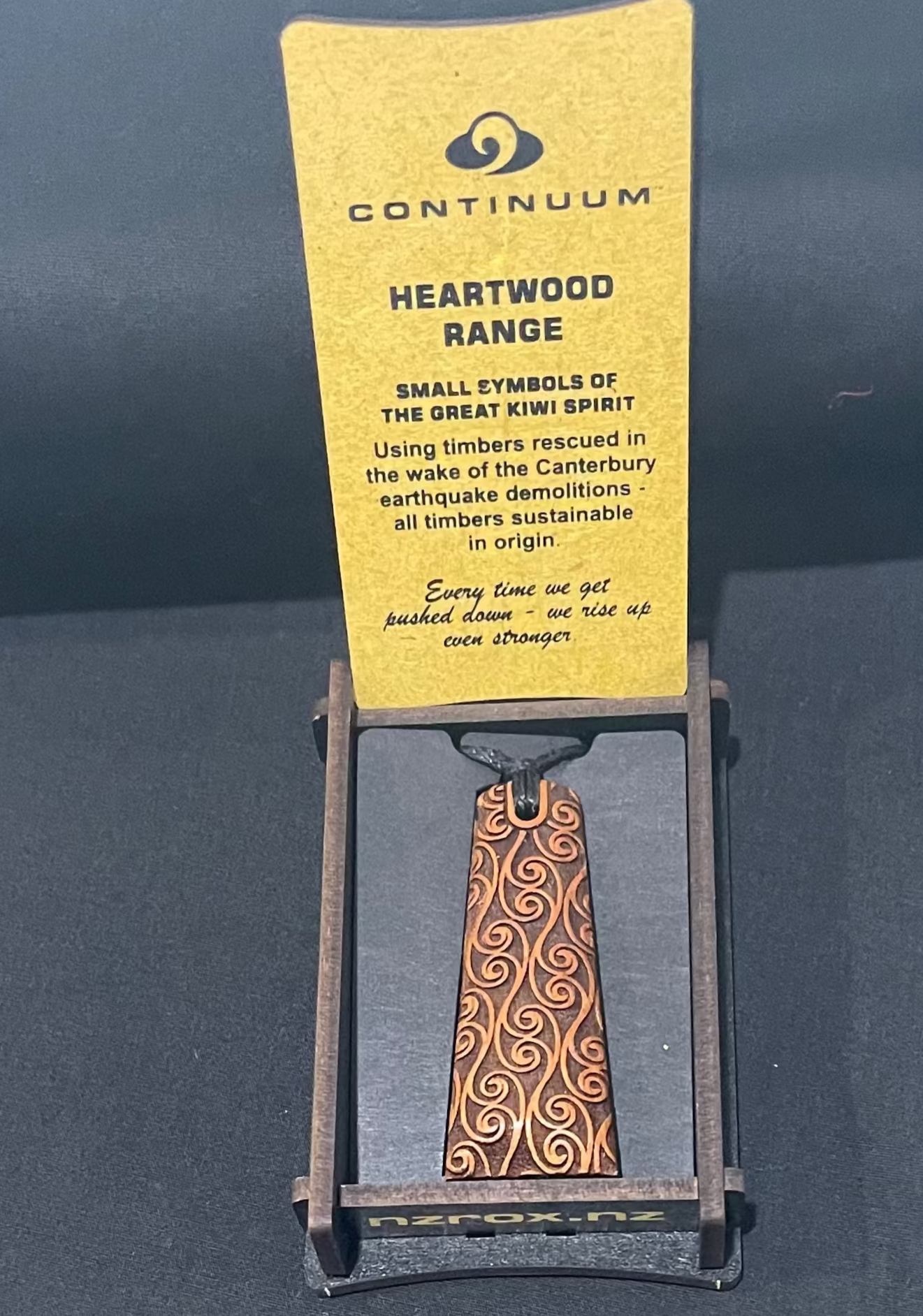 Wooden pendant on a Continuum branded card against a dark background