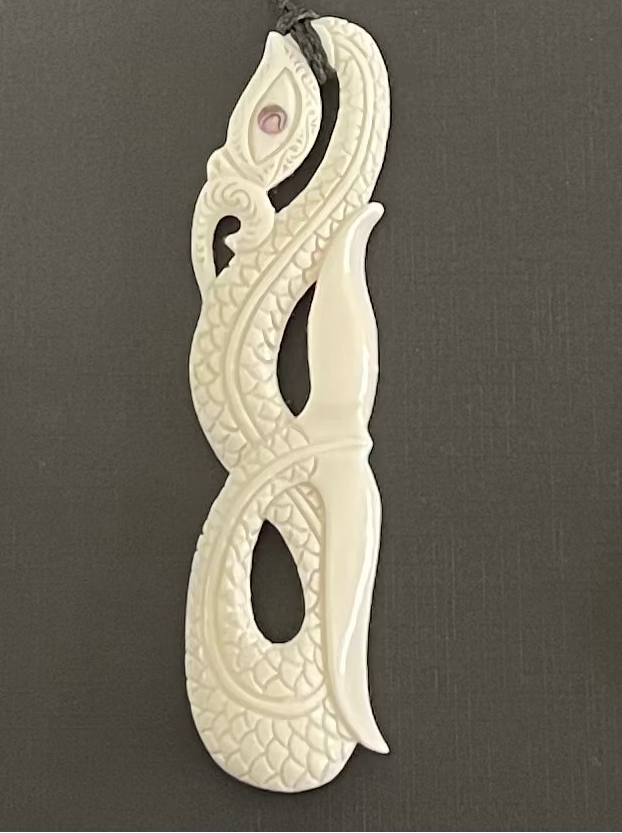 Decorative MANAIA pendant with intricate patterns on a gray background