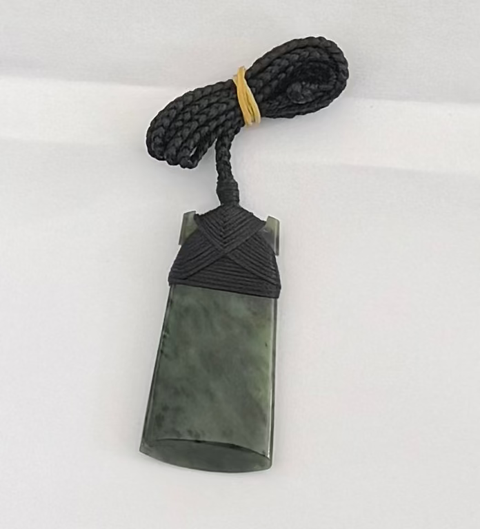 Green stone pendant with black cord on a white background