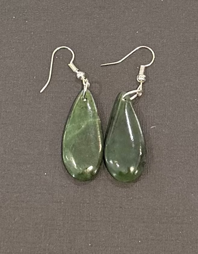 Teardrop-shaped greenstone earrings on a gray background