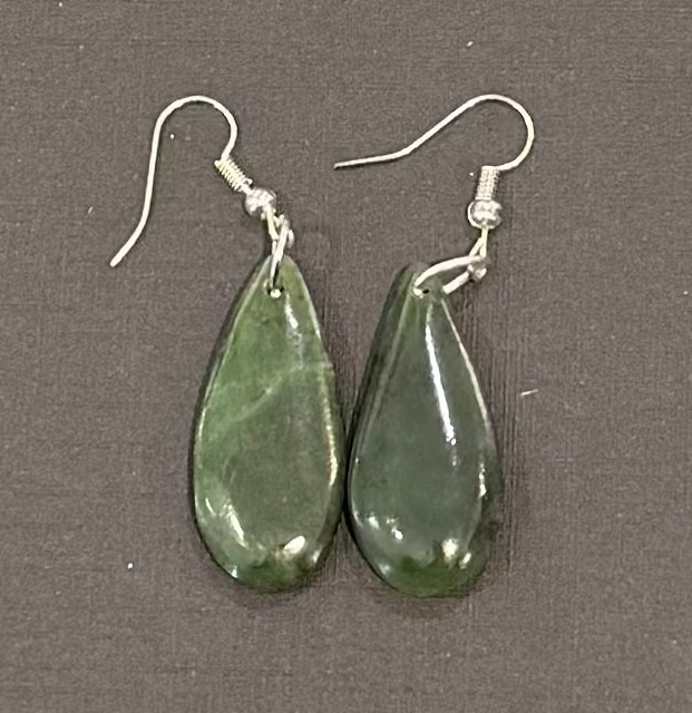 Teardrop-shaped greenstone earrings on a gray background