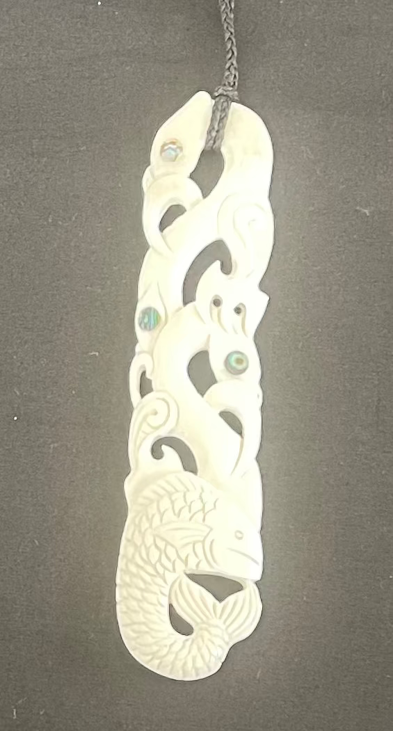 Carved bone pendant with intricate patterns on a dark background
