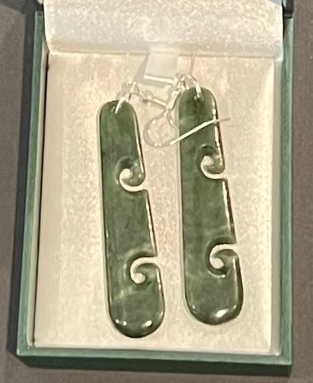 Pair of green jade earrings in a box on a gray background