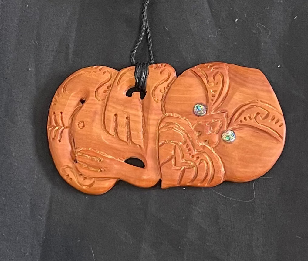 Wooden carving pendant with carvings on a black background