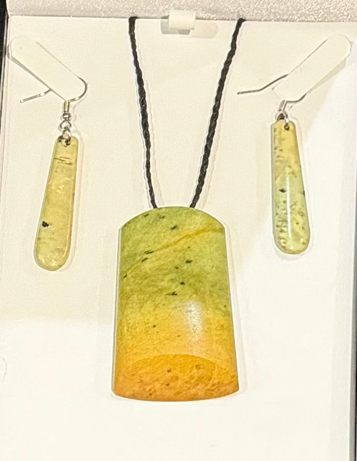 Jewelry set with greenstone pendant and earrings on a white background