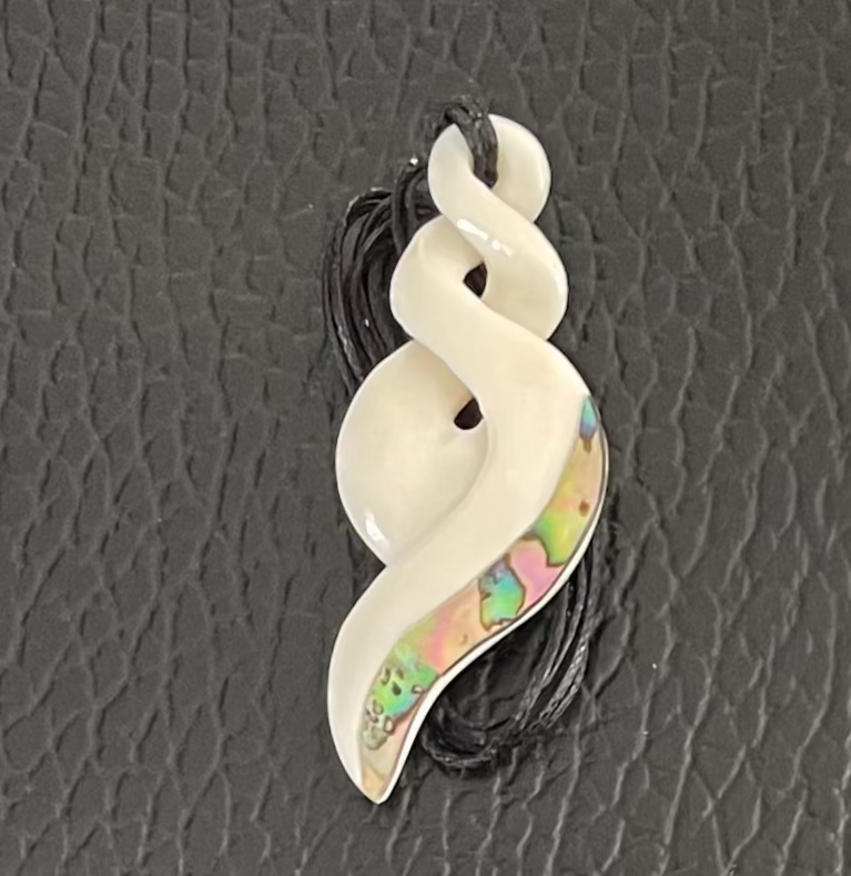 White spiral Twist bone pendant with paua interior on a black cord against a gray textured background
