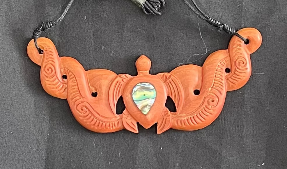 wooden carved necklace with intricate designs on a dark background