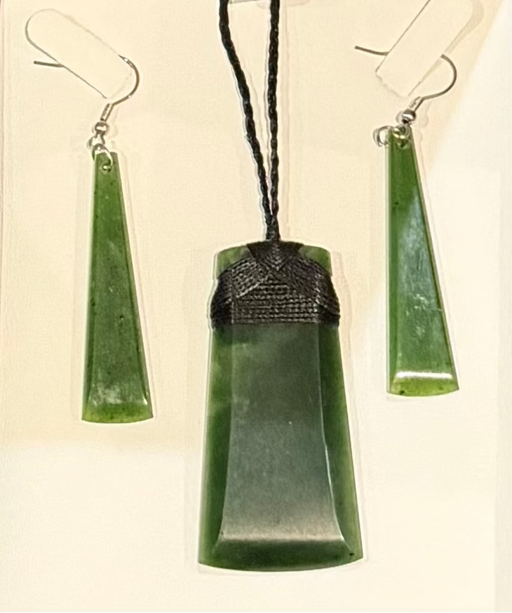 Greenstone pounamu jade pendant and earrings set on a white background