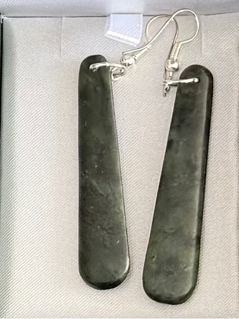 Pair of dark greenstone earrings on a light gray background