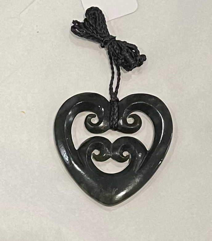 Heart-shaped pendant with intricate design on a white background