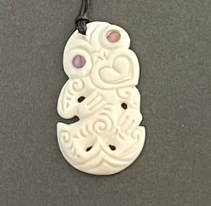 White bone carving pendant with purple stones on a gray background