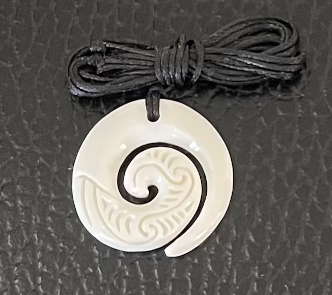 White spiral bone pendant on a black cord against a gray textured background