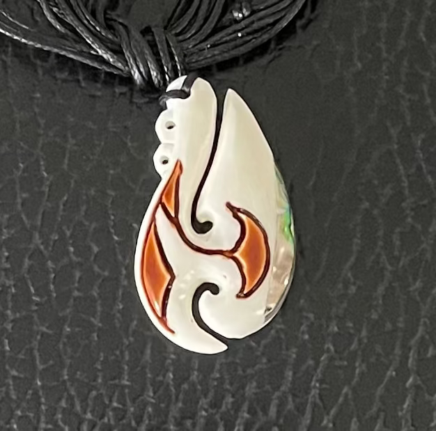 bone necklace pendant with orange design on a black cord against a textured black background