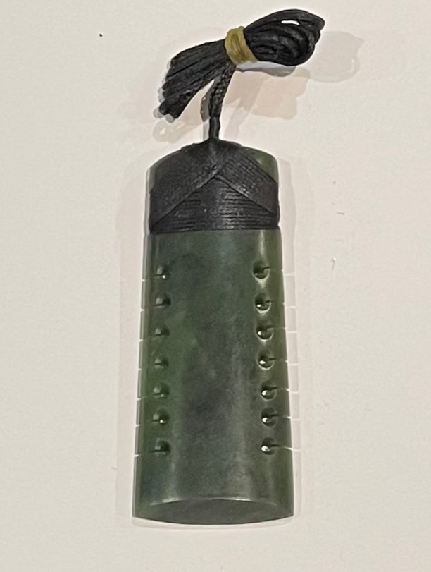Green stone pendant with decorative elements on a white background