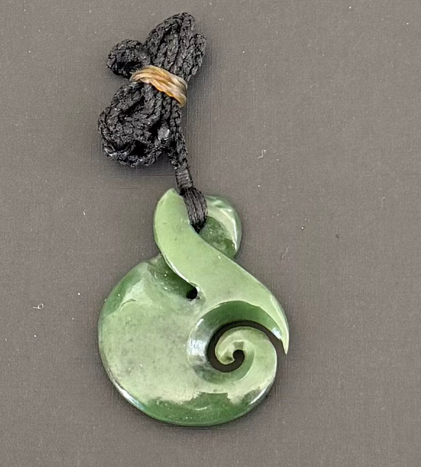 Green jade spiral pendant on a gray background
