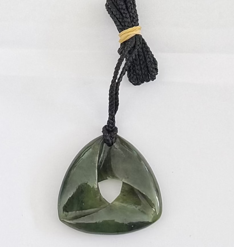 Green stone pendant on a black cord against a white background