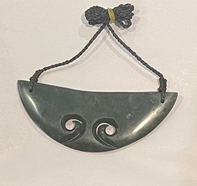 Greenstone pendant with spiral designs on a white background