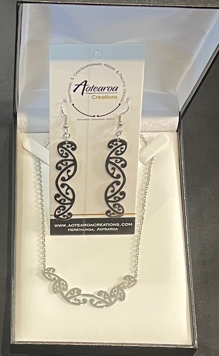 Maori Necklace with intricate design on a white card with brand name, against a dark background