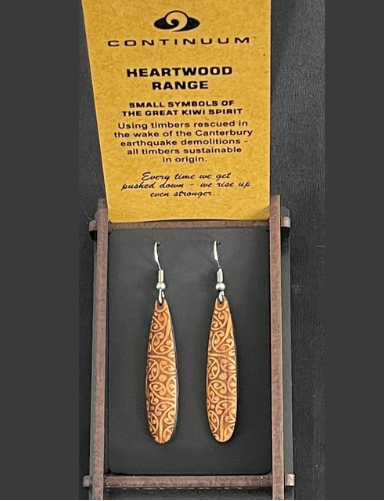 A pair of heartwood earrings displayed in a card with the brand name Continuum, stating that they are made from the great kiwi spirit timbers of Canterbury, New Zealand.