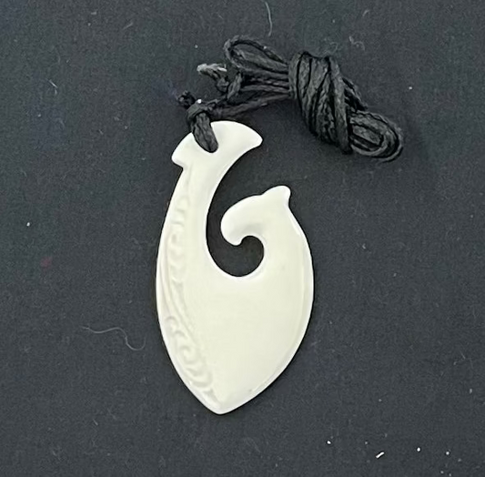 White bone pendant with spiral design on a black background