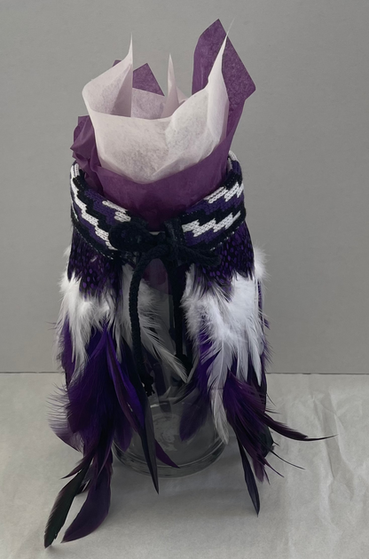 Decorative purple and white korowai on a gray background