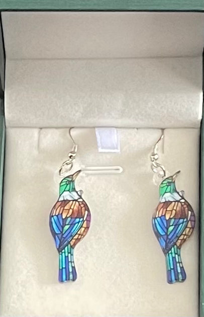 Colorful tui bird-shaped earrings on a light gray background