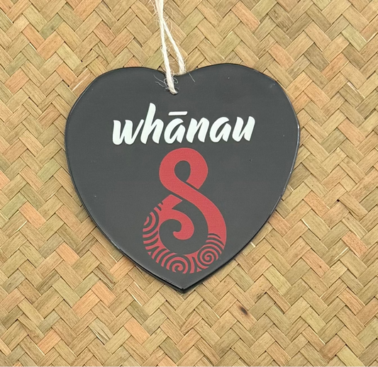 Heart-shaped tag with 'whánau' and a red design on a woven background