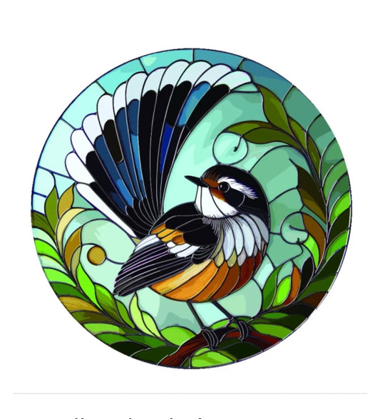 A circular stained-glass style artwork of a bird perched on a branch, surrounded by green leaves, with blue, black, white, orange, and yellow details on a white background.