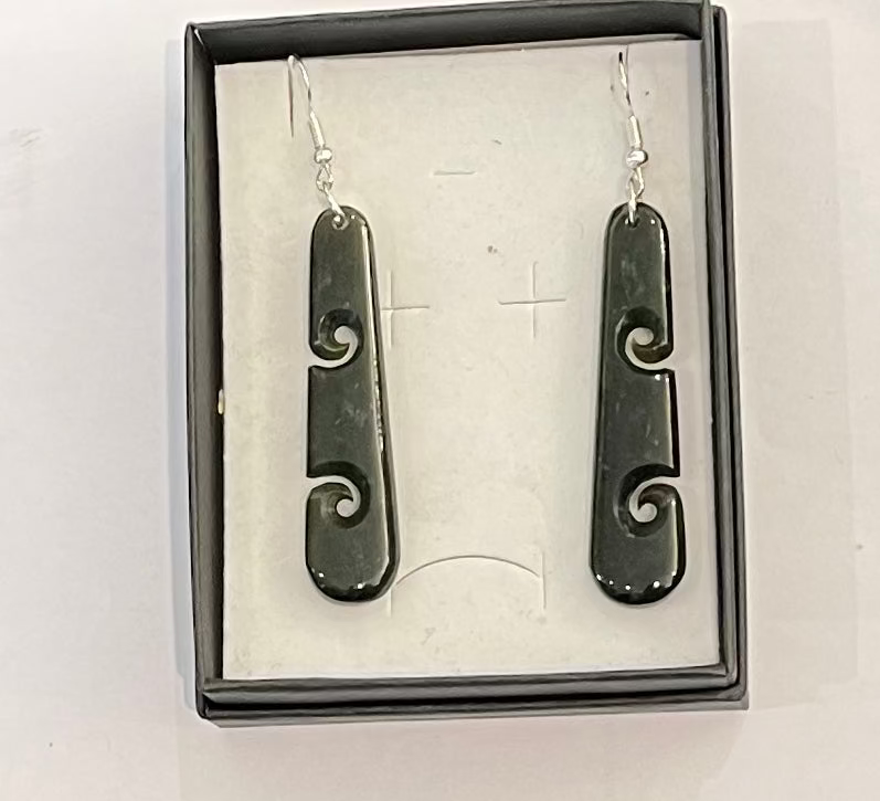 Pair of greenstone earrings with silver hooks in a box on a white background