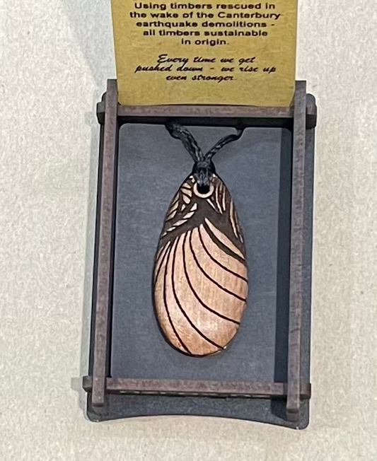 Wooden pendant on a gray stand with a card behind it