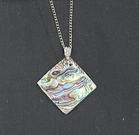 paua Necklace with a square, multicolored shell pendant on a dark background