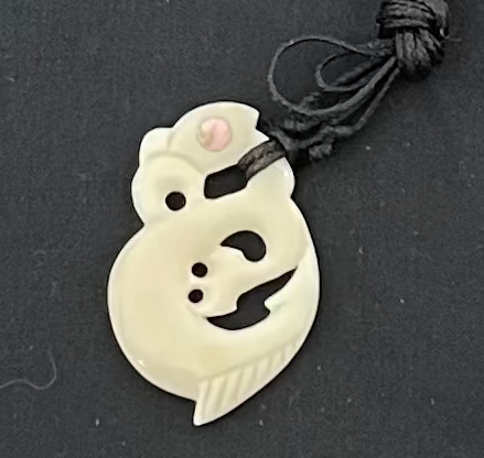 White bone pendant on a black cord against a black background