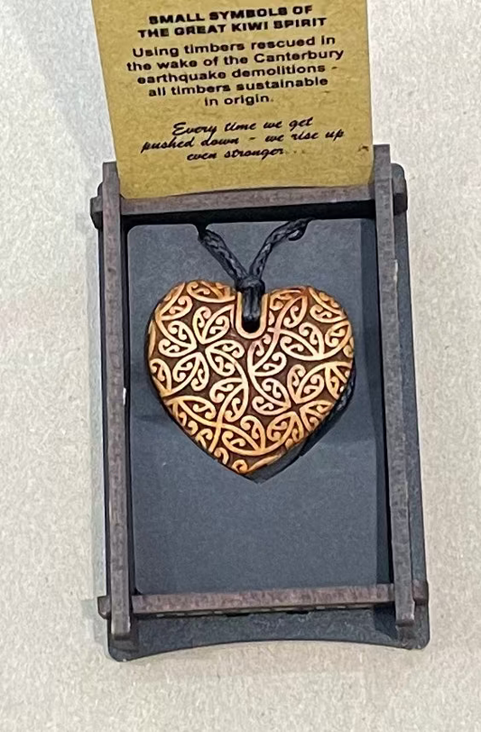 Heart-shaped pendant with intricate design on a card with text