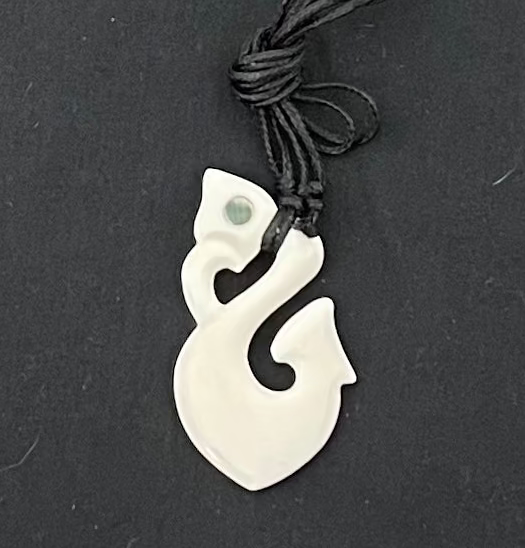 White fish hook pendant on a black background