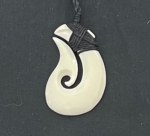 White bone pendant with black cord on a dark gray background