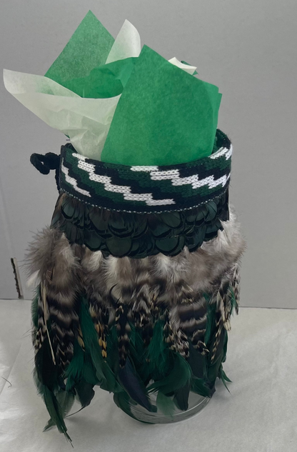 Decorative jar with green feathers and a patterned band on a white background