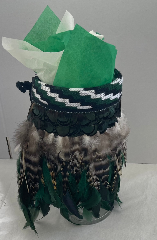 Decorative jar with green feathers and a patterned band on a white background