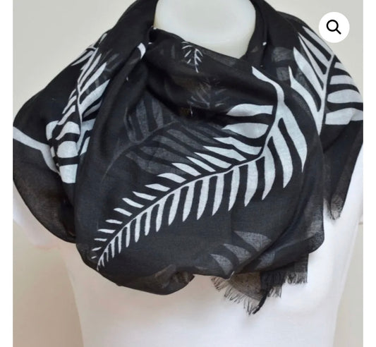 A lightweight black scarf with a white tropical palm leaf pattern, draped on a white mannequin torso.