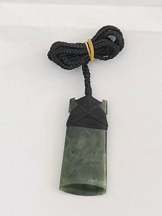 Green stone pendant with black cord on a white background